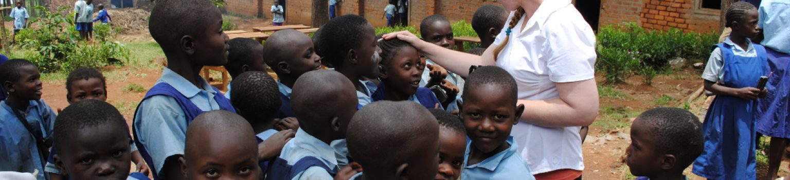 Volunteer surrounded by smiling schoolchildren